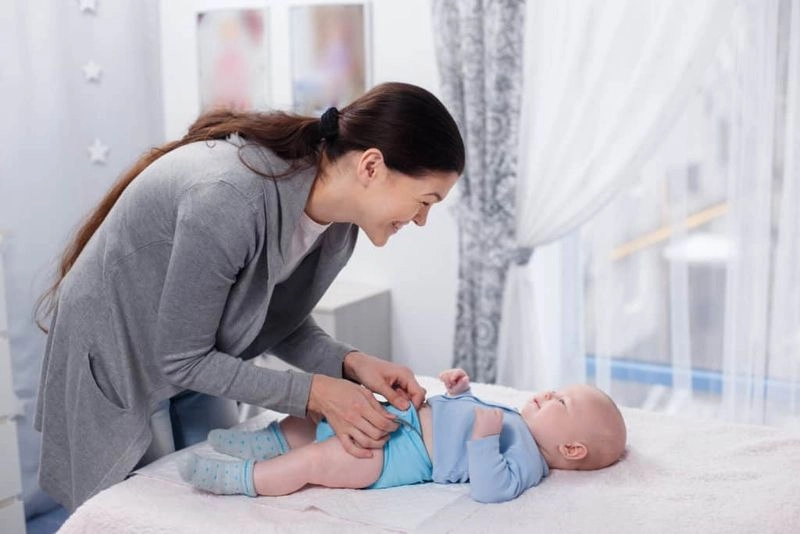 mẹ kiểm tra tấm lót chống thấm cũi em bé