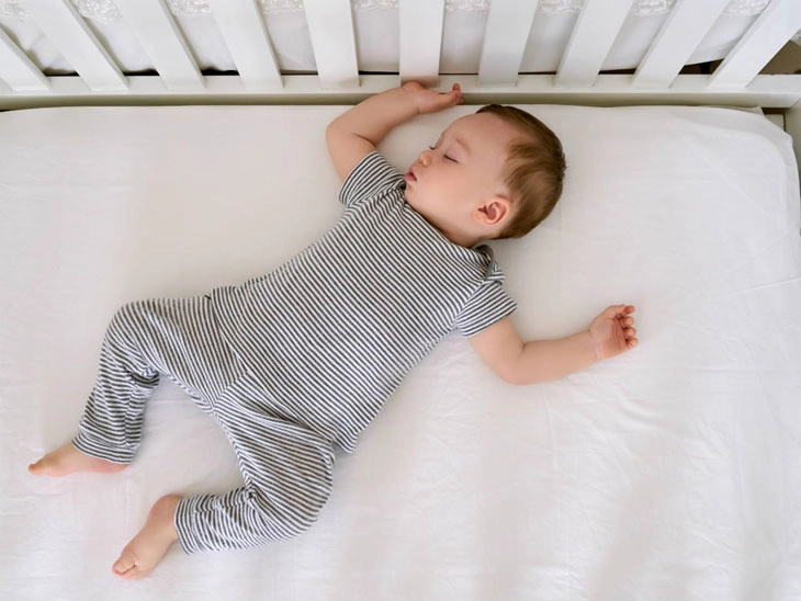 Bé sơ sinh ngủ ngửa trên nệm cứng vừa